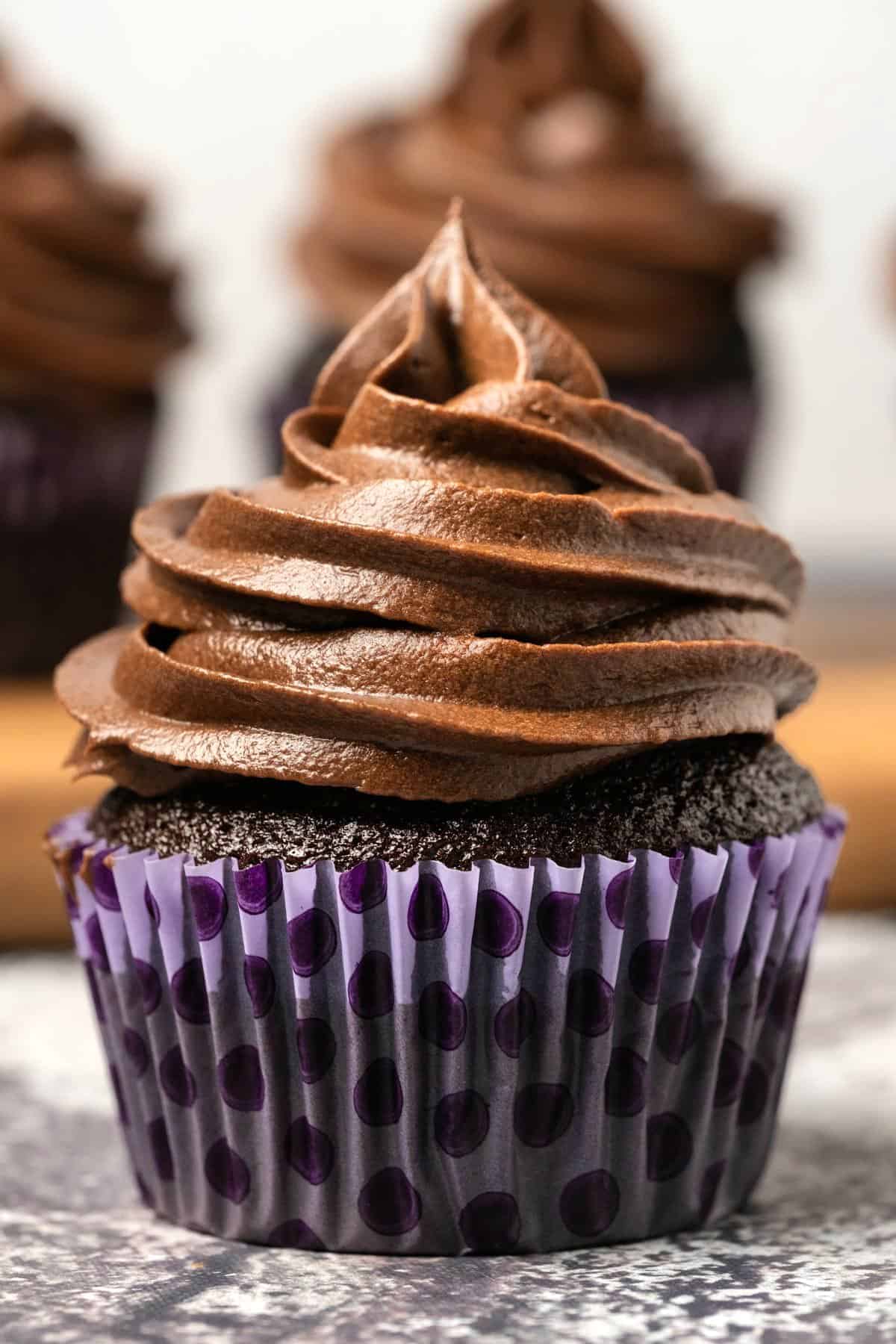 Cupcake with chocolate buttercream frosting piped on top. 