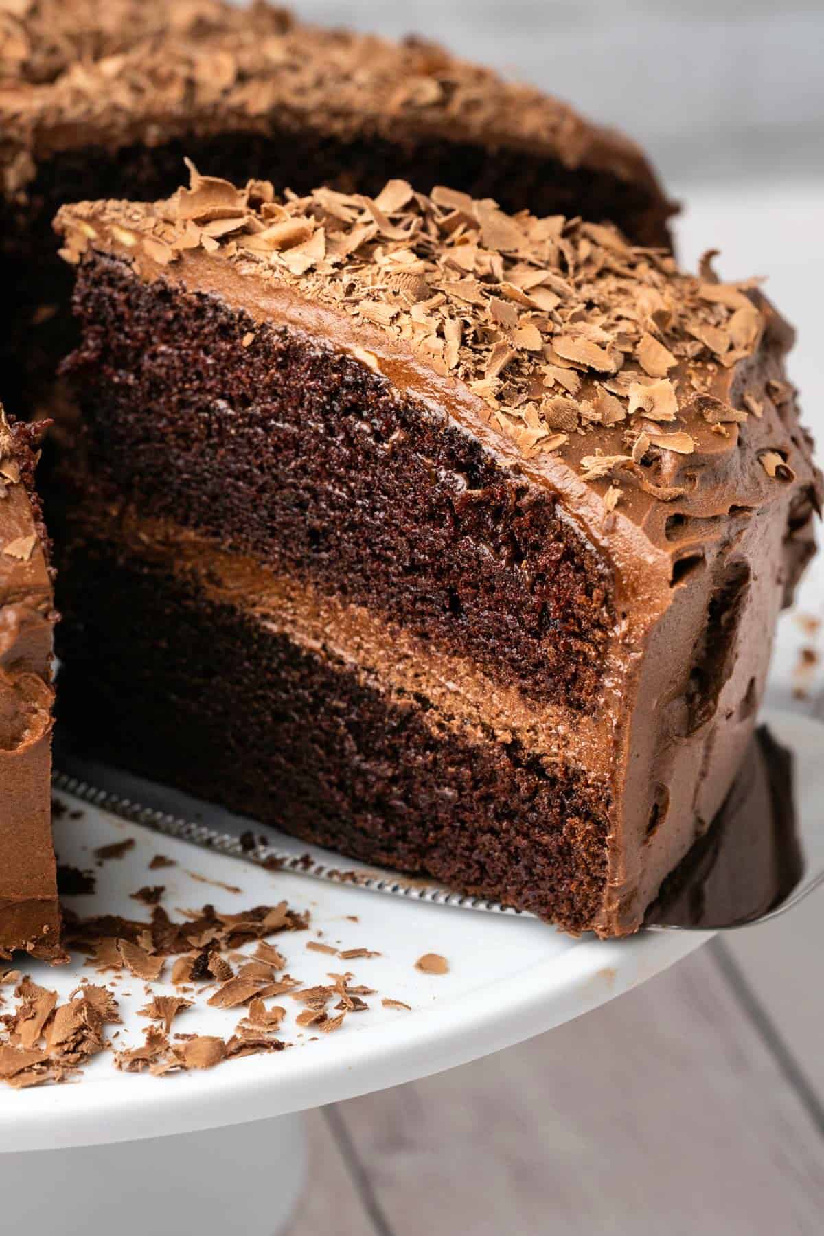 Sliced chocolate cake on a white cake stand. 