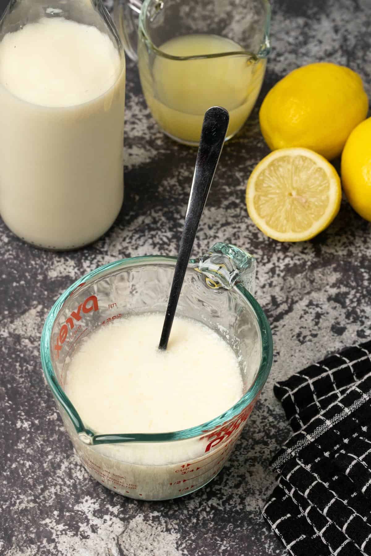 Homemade buttermilk in a glass measuring jug with a spoon. 