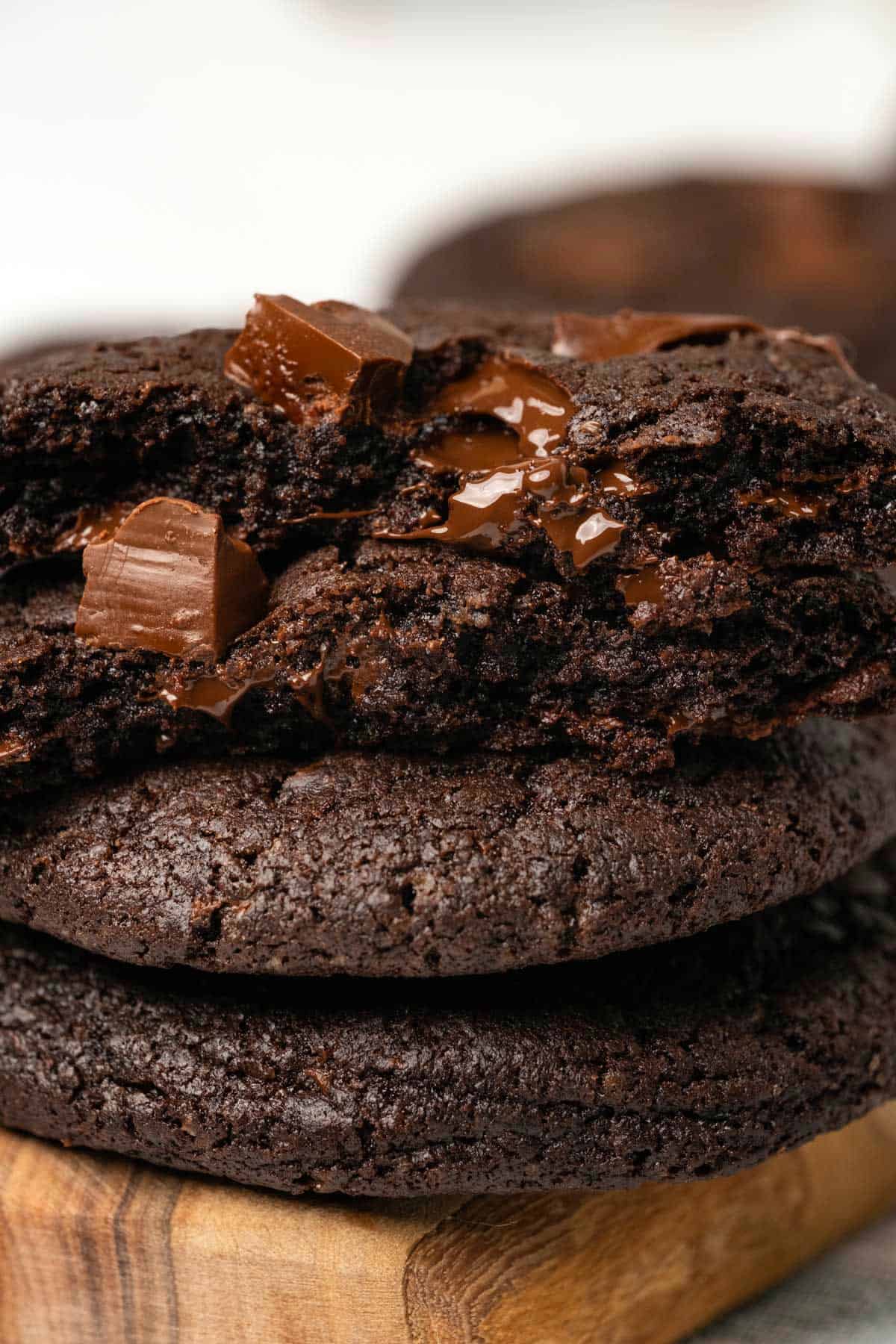 Chocolate cookies in a stack with the top cookie broken in half to show the center. 