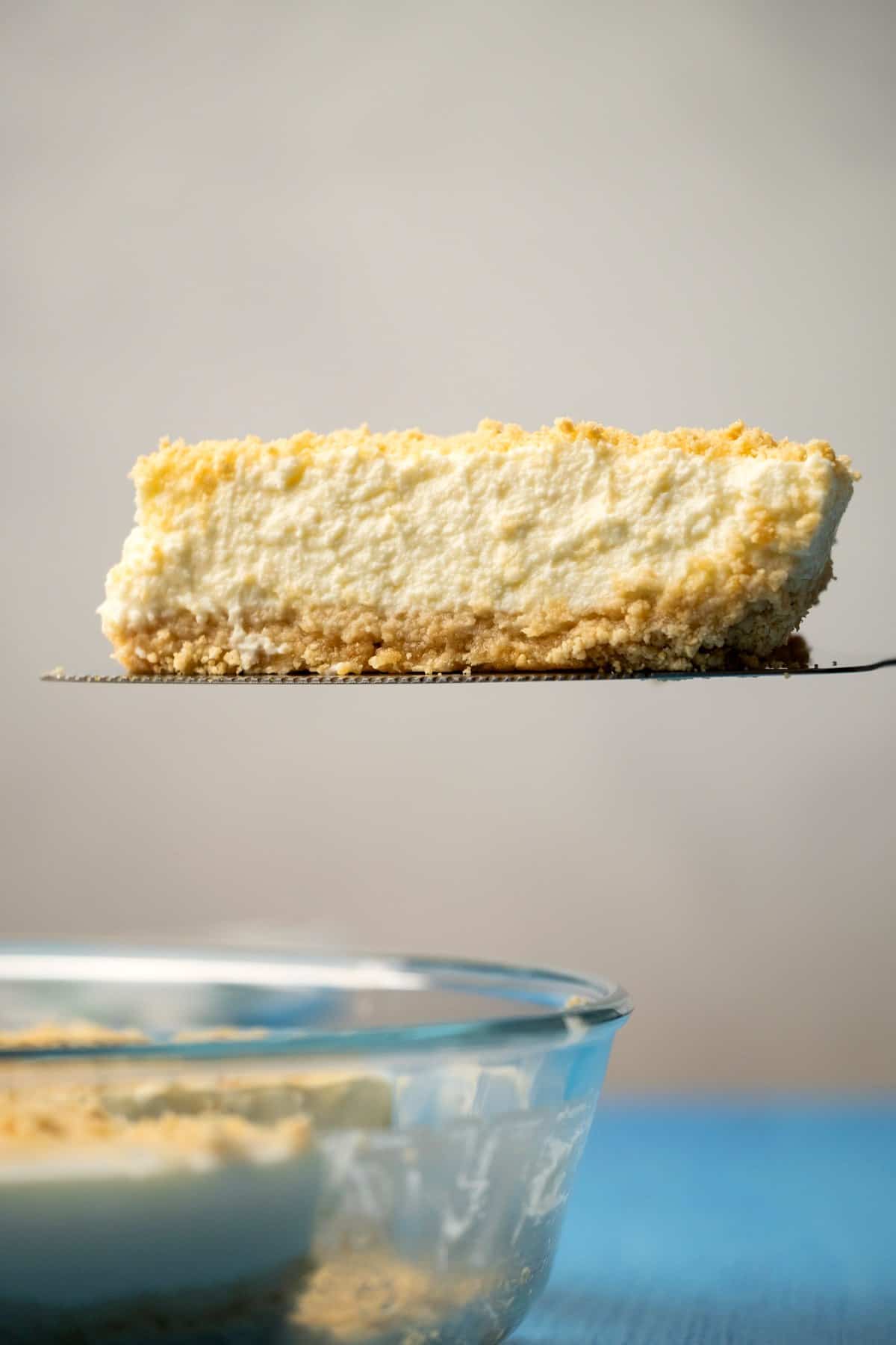 A slice of cheesecake on a cake lifter. 