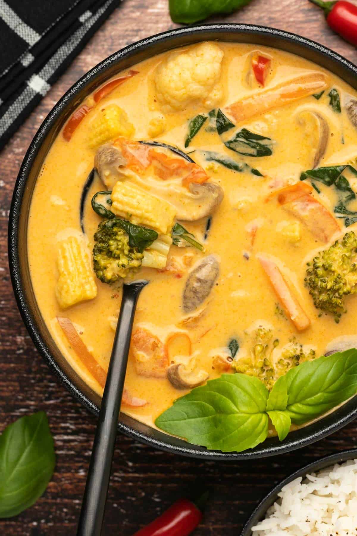 Thai red curry with fresh basil in a bowl with a spoon. 