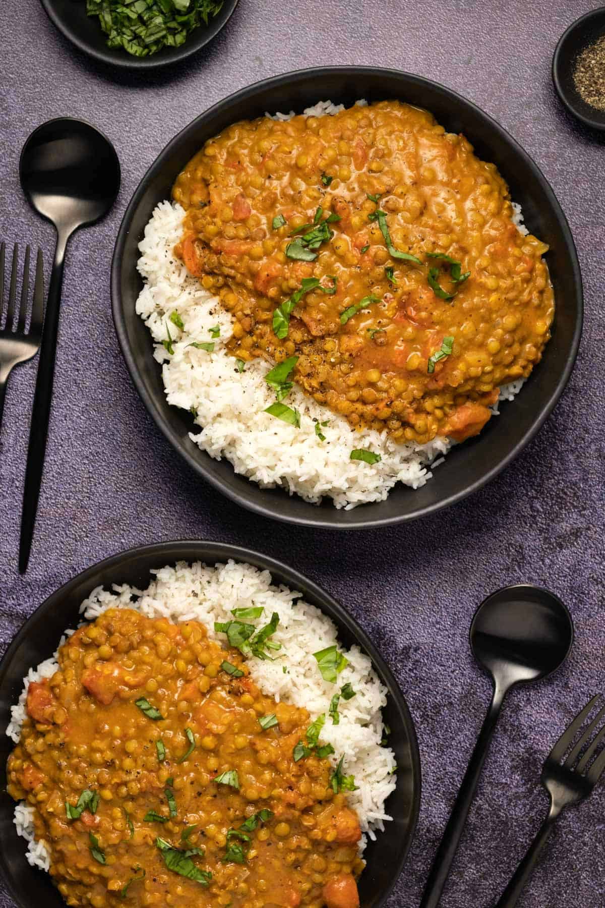 Lentil curry with rice in black bowls. 