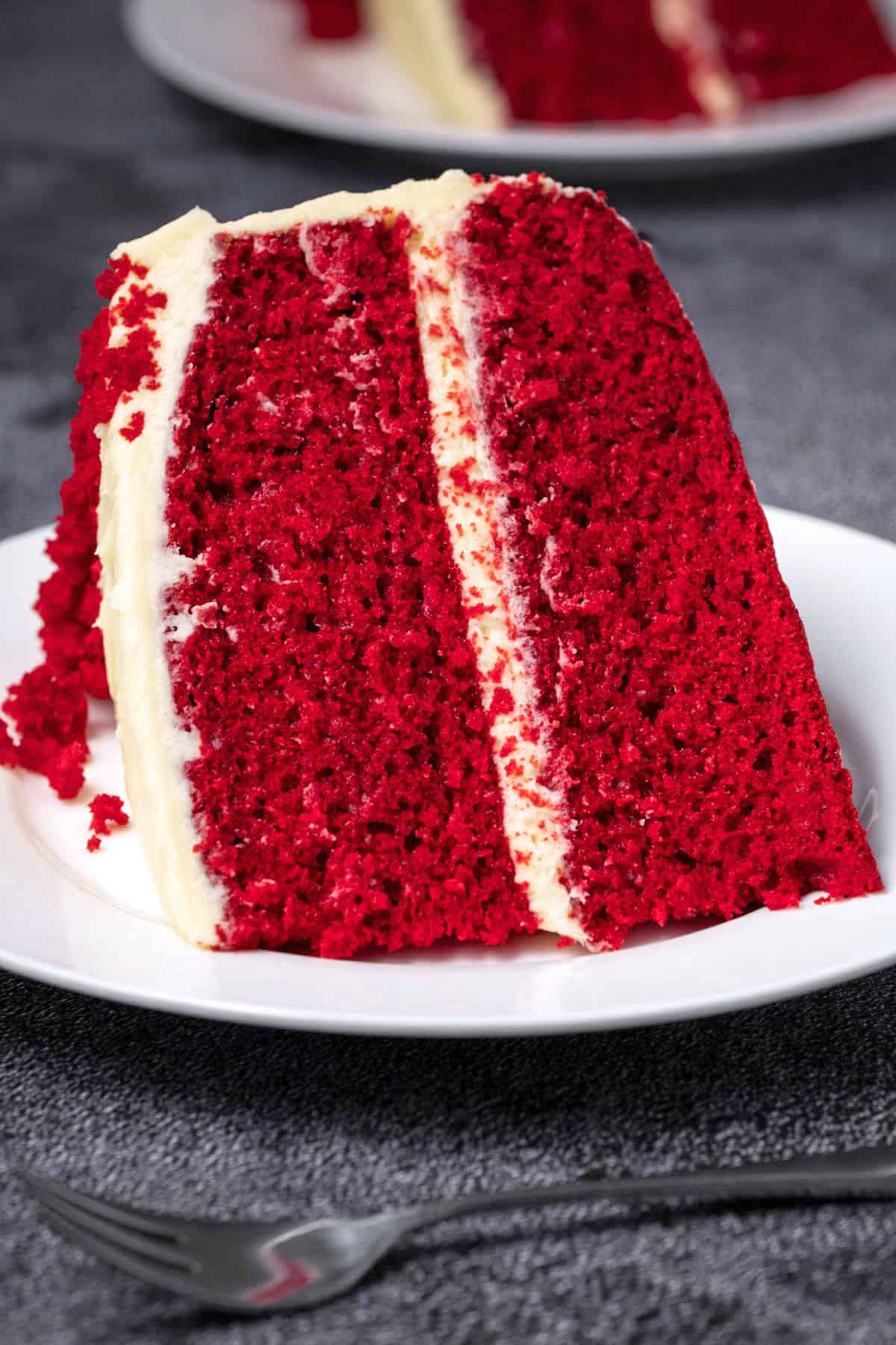 Slice of red velvet cake on a white plate. 