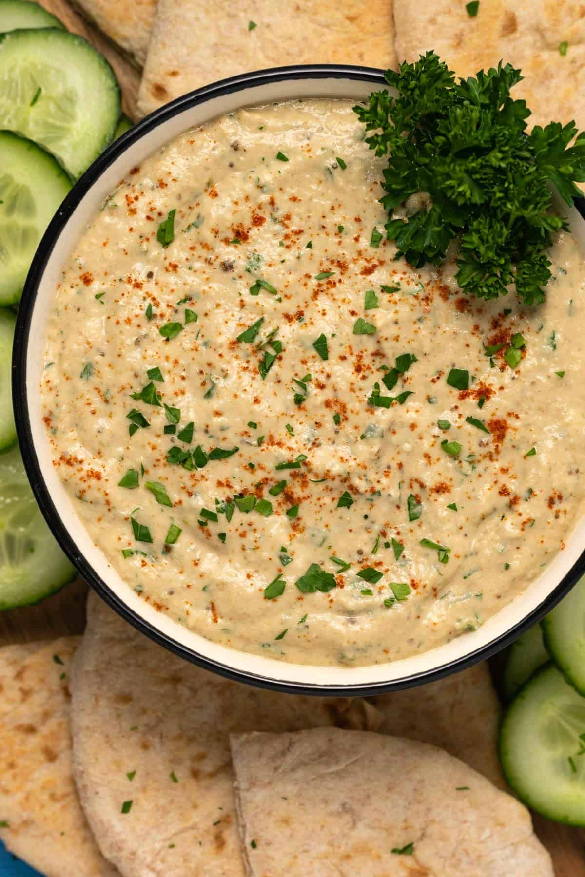 Eggplant dip in a ceramic bowl with fresh parsley and smoked paprika.