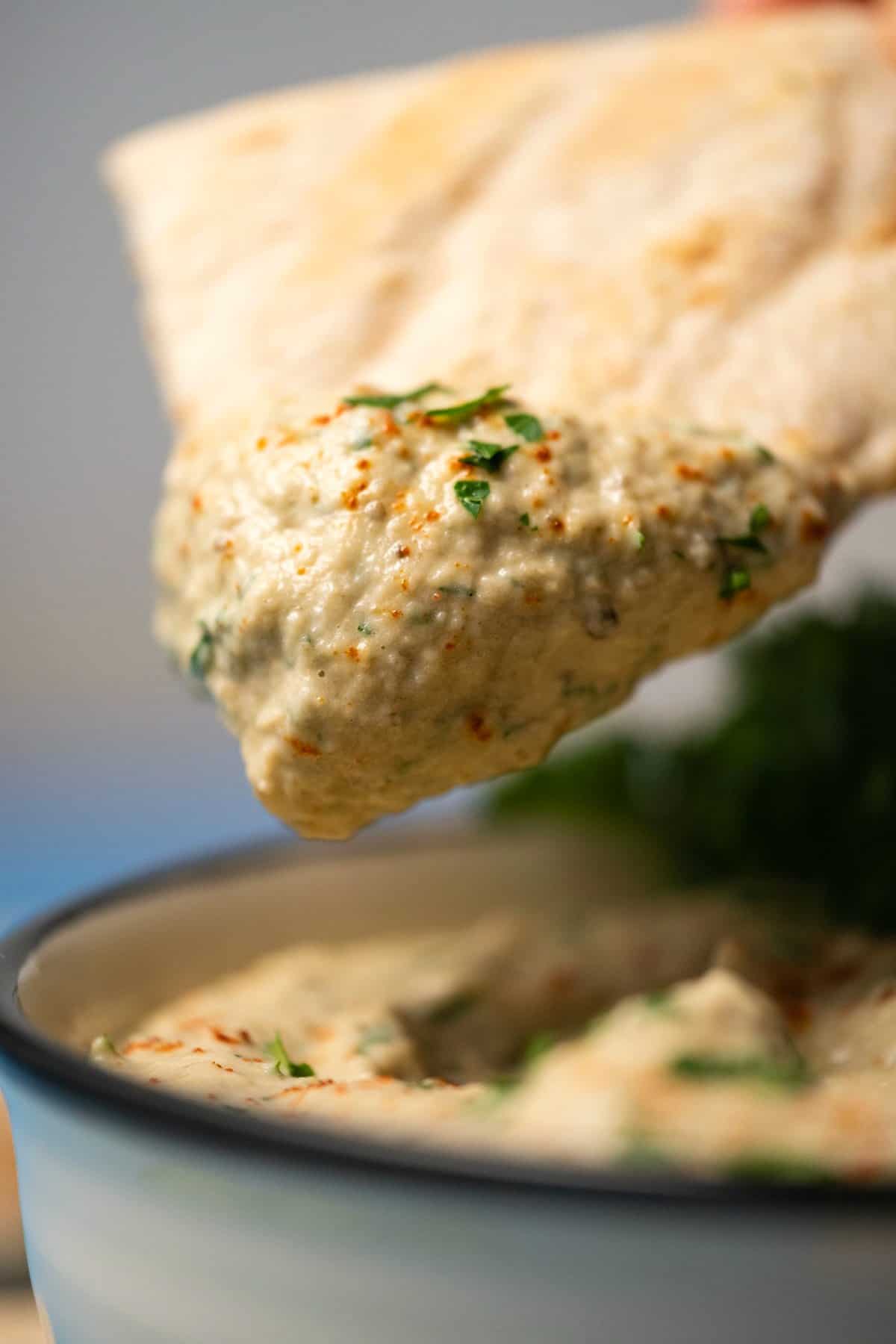 Pita bread dipping into a bowl of baba ganoush. 