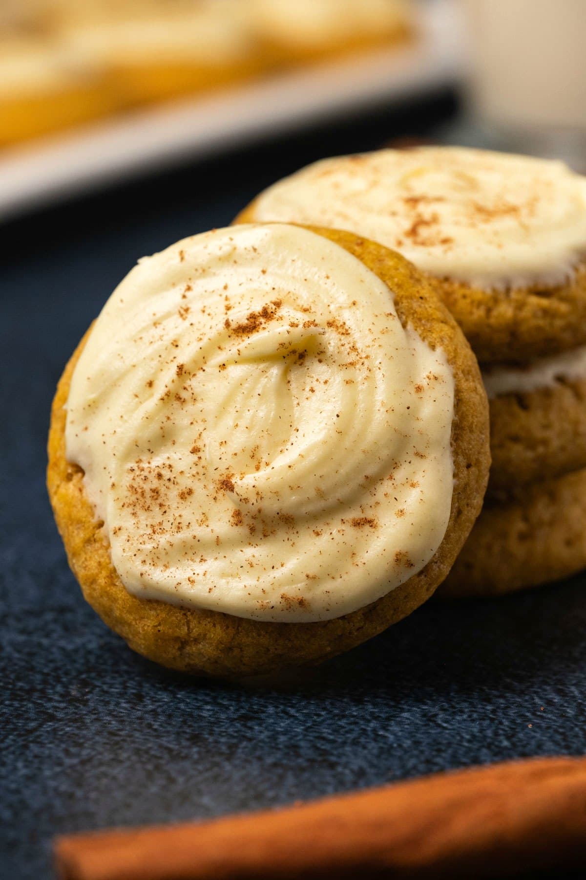 Pumpkin cookies with cream cheese frosting in a stack. 