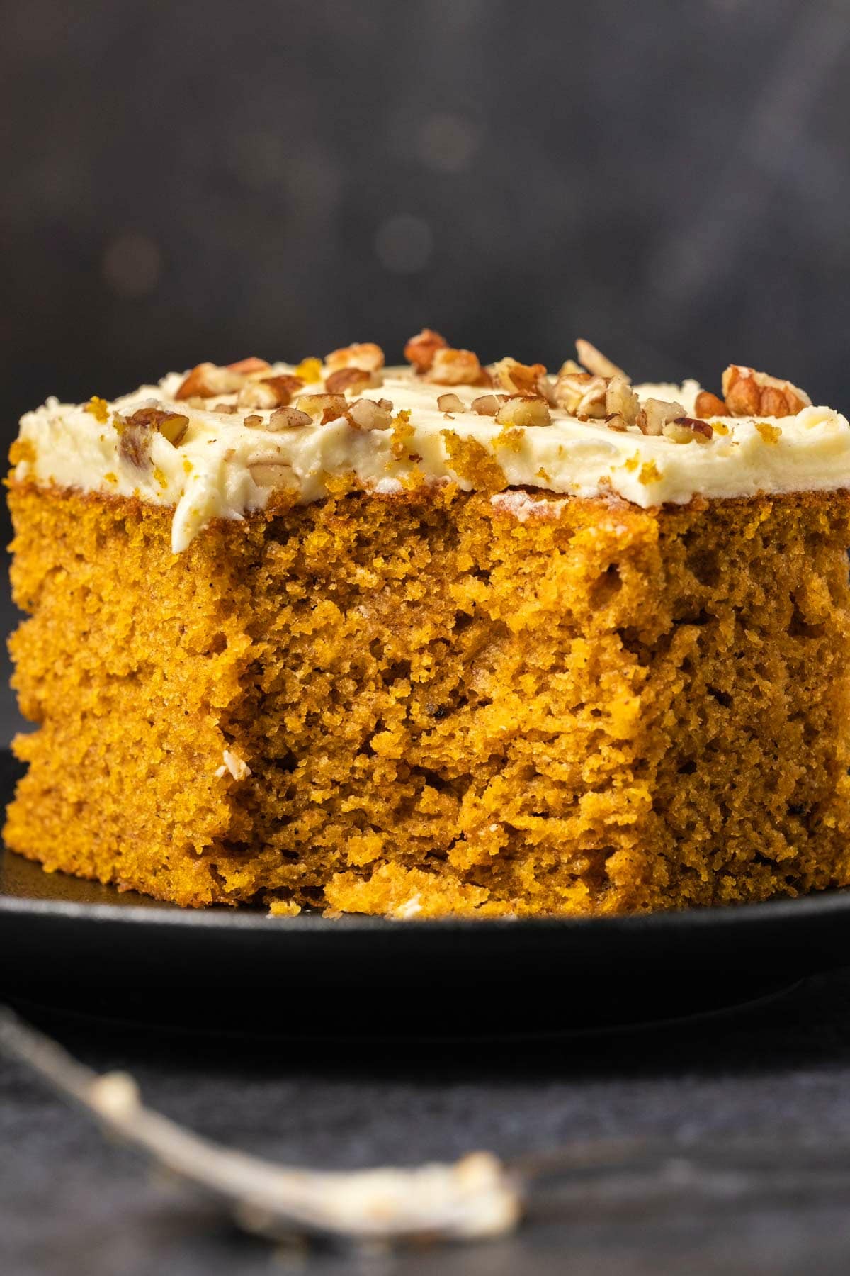 Slice of pumpkin cake on a black plate.