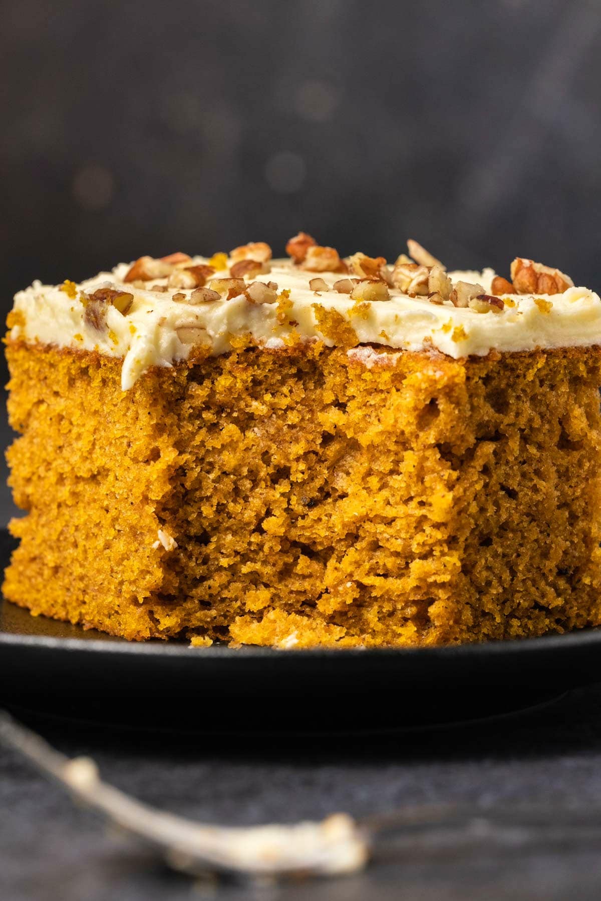 Slice of pumpkin cake on a black plate. 