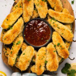 Baked jalapeño poppers on a wooden board.