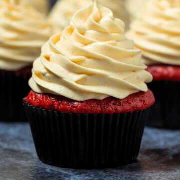 Red velvet cupcakes with piped frosting on top.