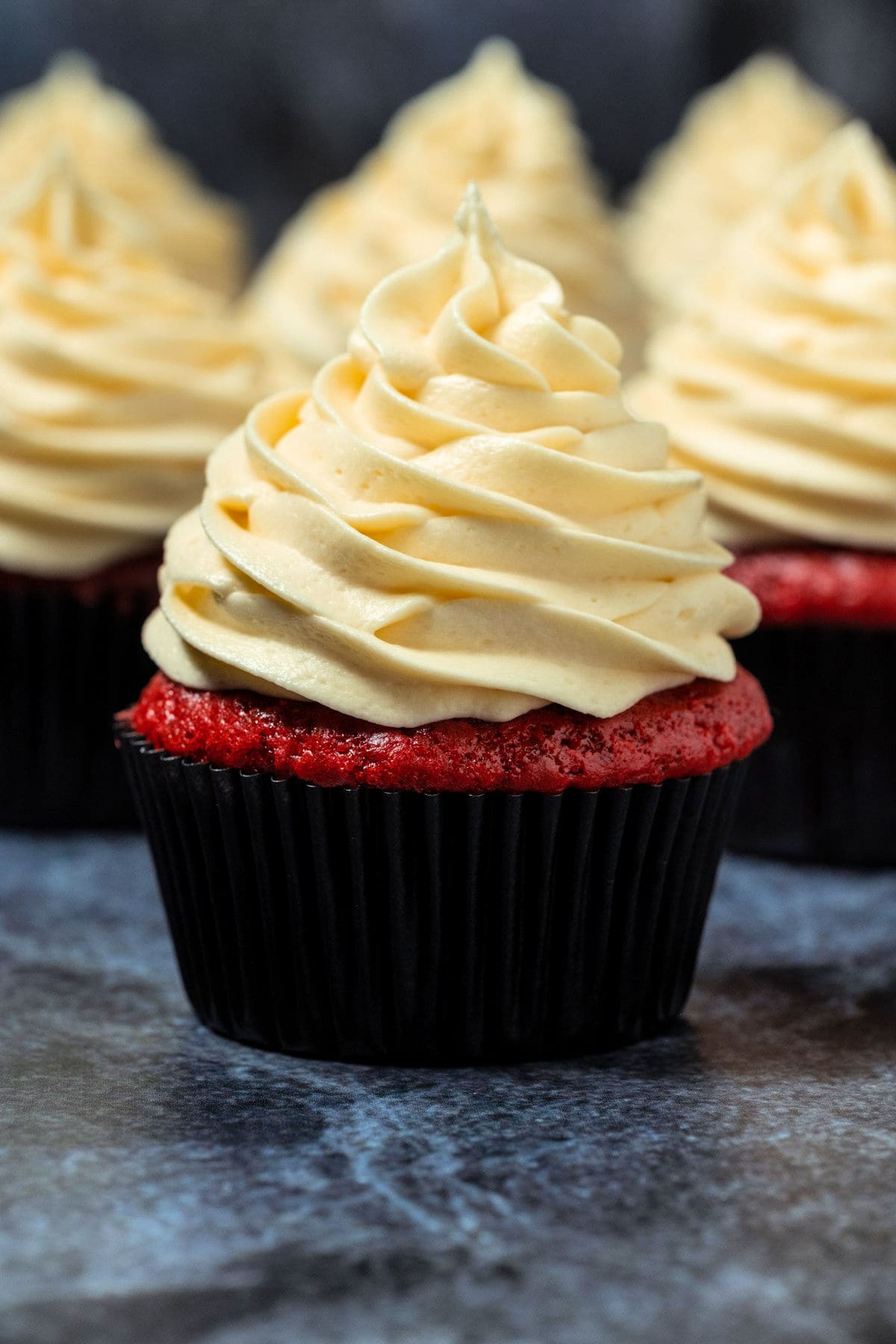 Red velvet cupcakes with piped frosting on top.