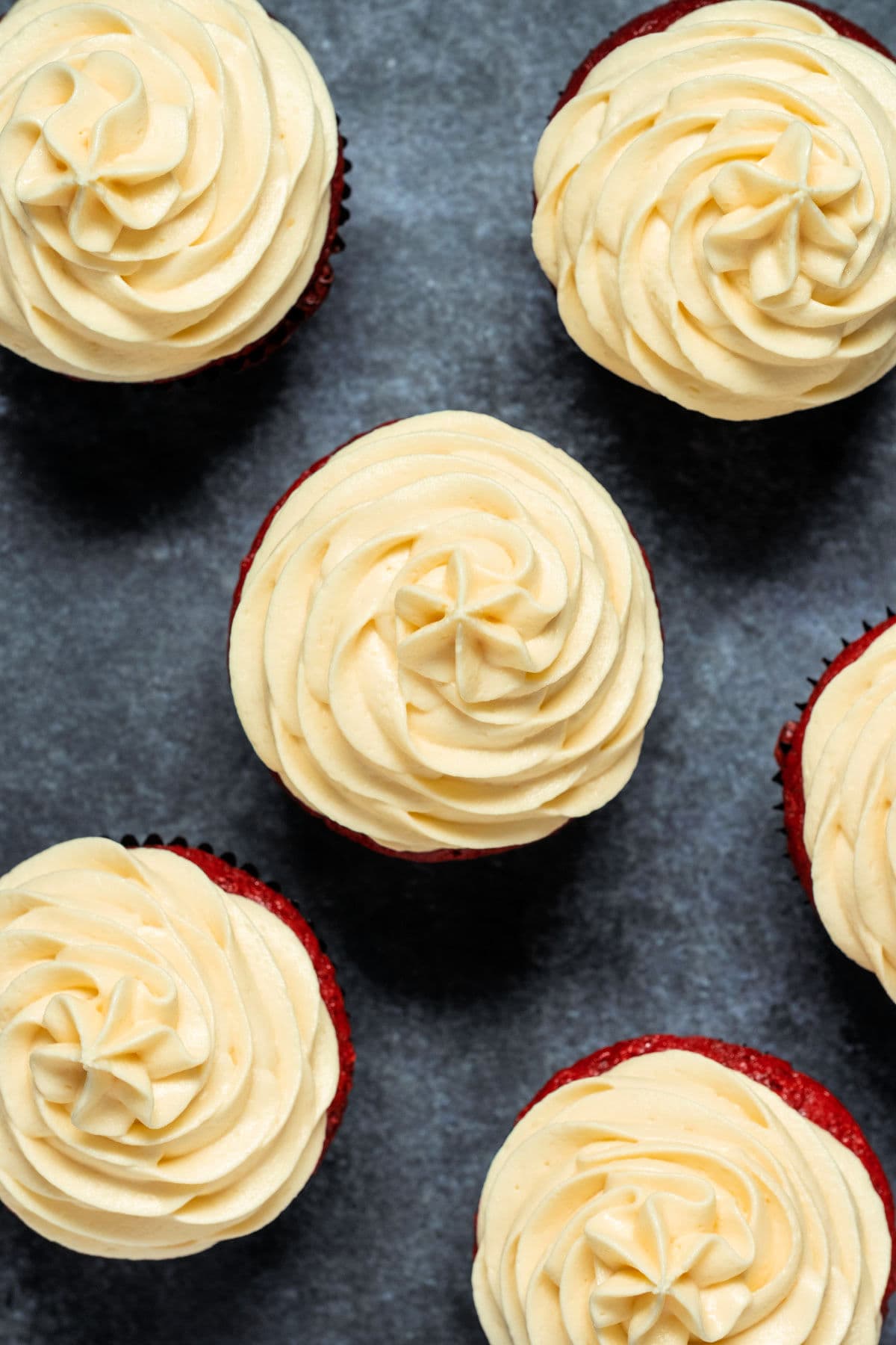 Overhead photo of cupcakes topped with white chocolate cream cheese frosting.