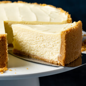 Eggless cheesecake on a white cake stand with one slice ready to serve.