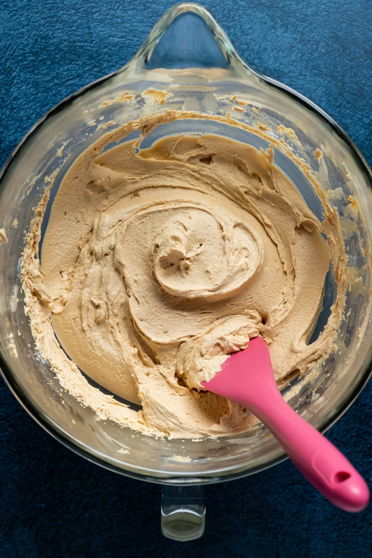 Biscoff buttercream frosting in a bowl with a pink spatula.