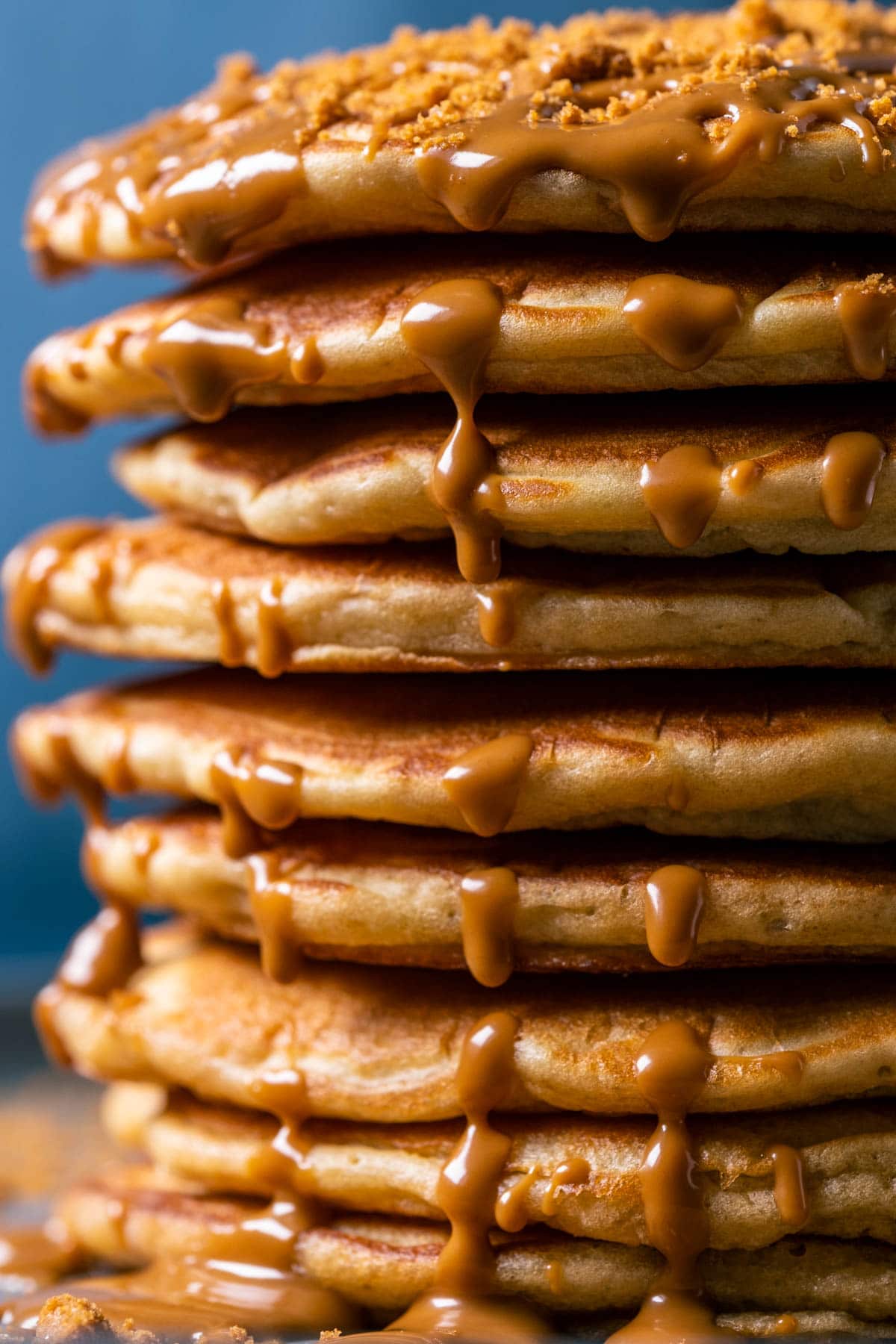 Stack of biscoff pancakes drizzled with melted biscoff on a gray plate.