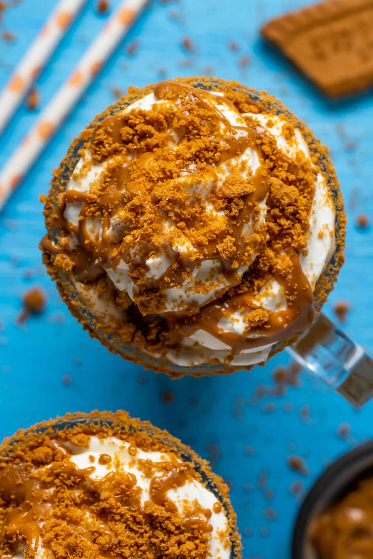 Biscoff milkshakes in glasses topped with whipped cream, melted biscoff cookie butter and crushed biscoff cookies.
