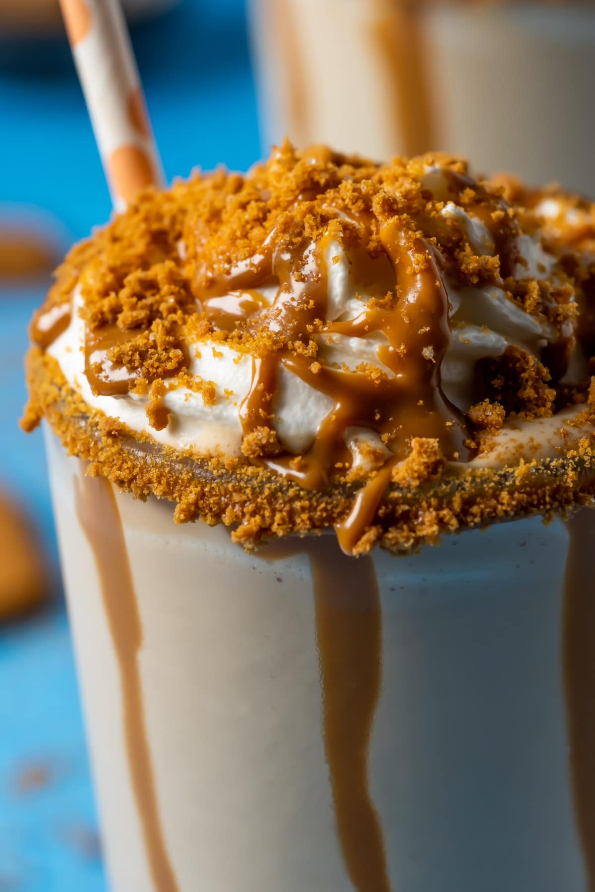 Biscoff milkshakes in glasses topped with whipped cream, melted biscoff cookie butter and crushed biscoff cookies.