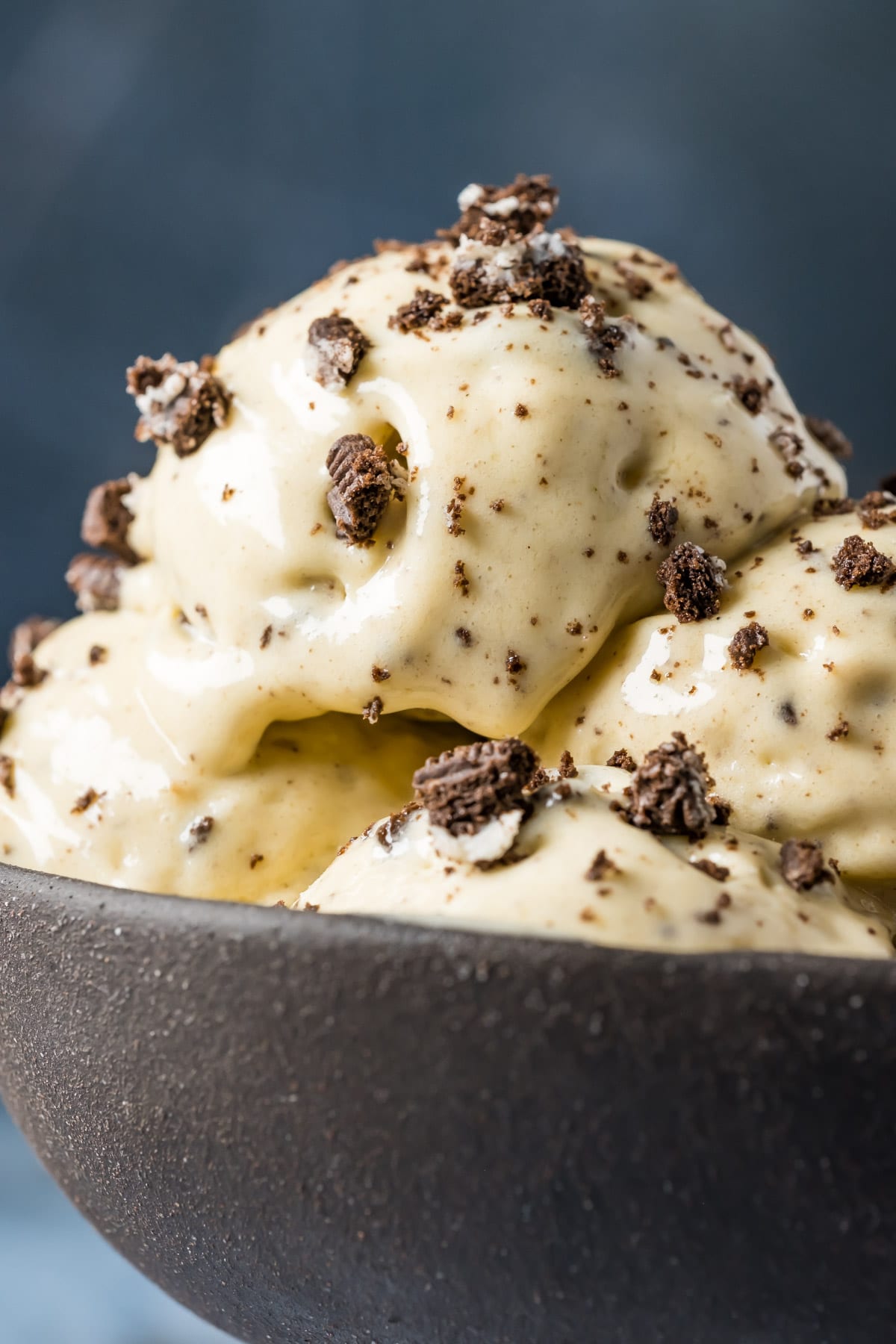 Scoops of cookies and cream nice cream in a black bowl.