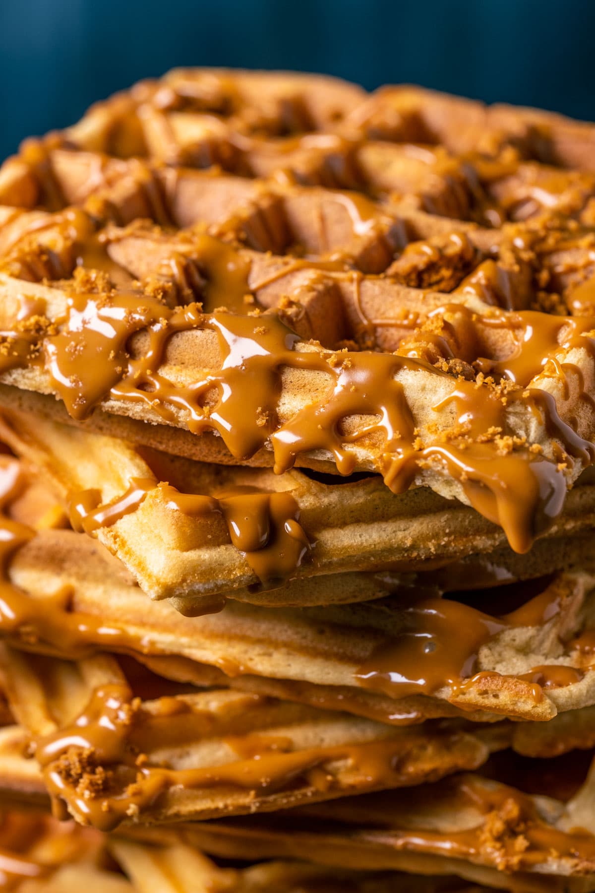Stack of biscoff waffles with drizzled melted biscoff on a gray plate.