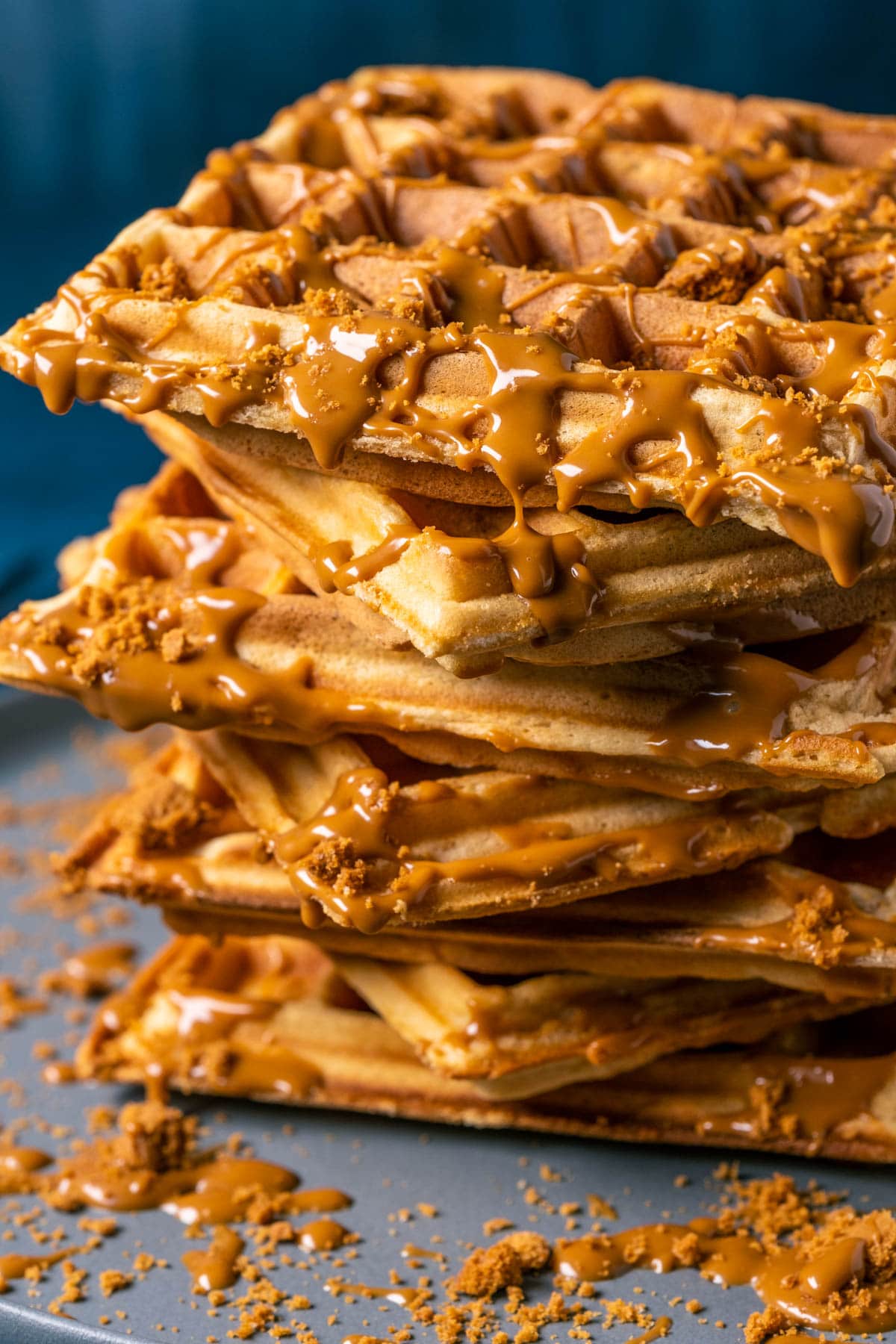 Stack of biscoff waffles with drizzled melted biscoff on a gray plate.