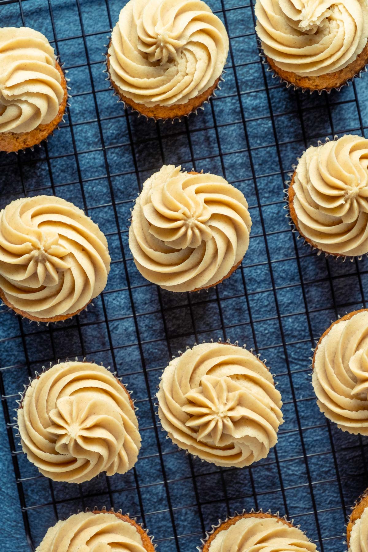 Frosted cinnamon cupcakes on a wire cooling rack.