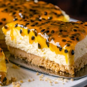 Sliced passion fruit cheesecake on a white cake stand.