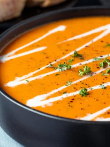 Tomato soup in a black bowl.