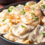 Halloumi stroganoff topped with chopped parsley in a black bowl.
