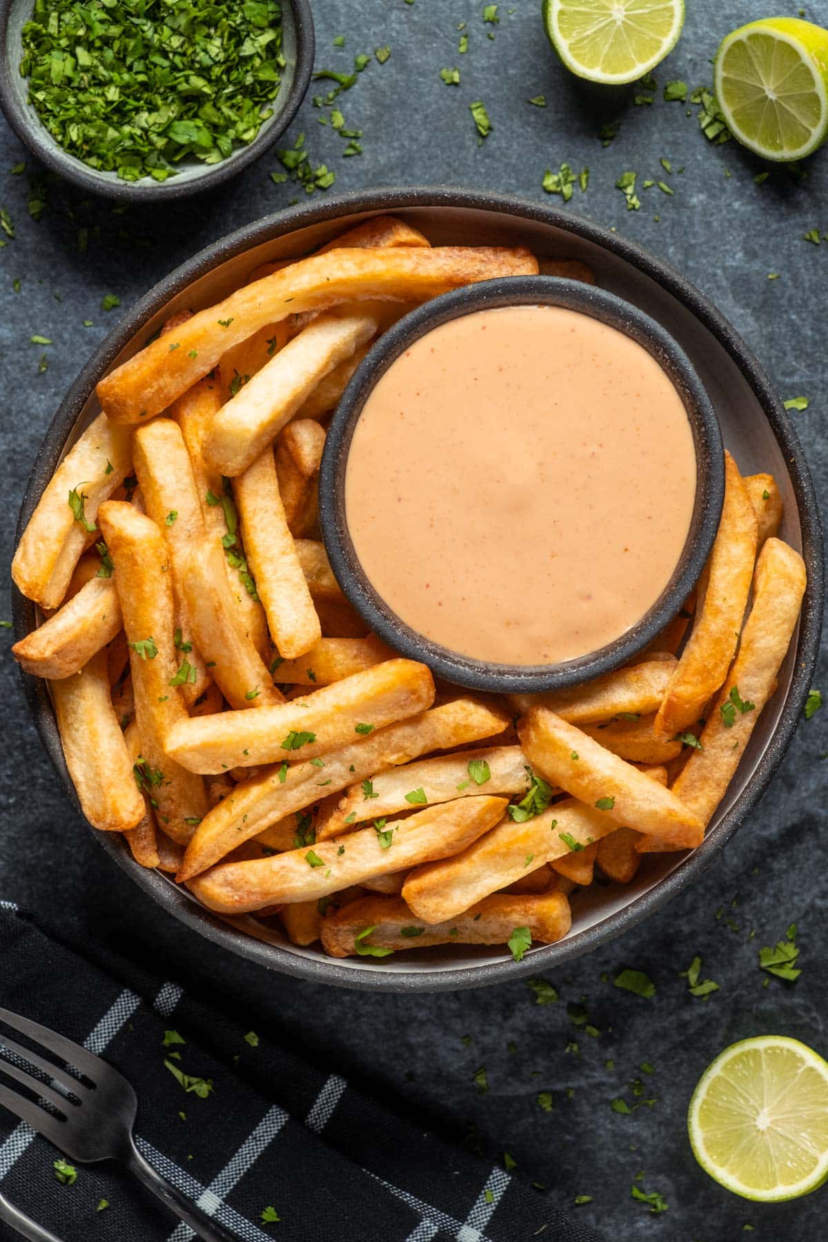 Aioli in a bowl surrounded by fries. 